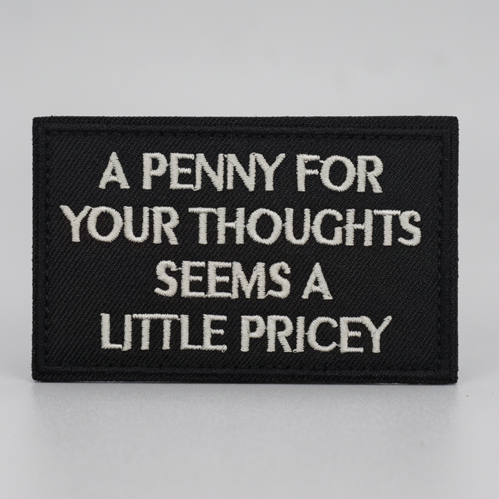 A Penny For Your Thoughts black embroidered patch on a light grey studio surface